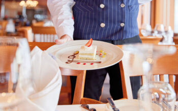 Kellner auf MS HAMBURG präsentiert Dessert im Restaurant